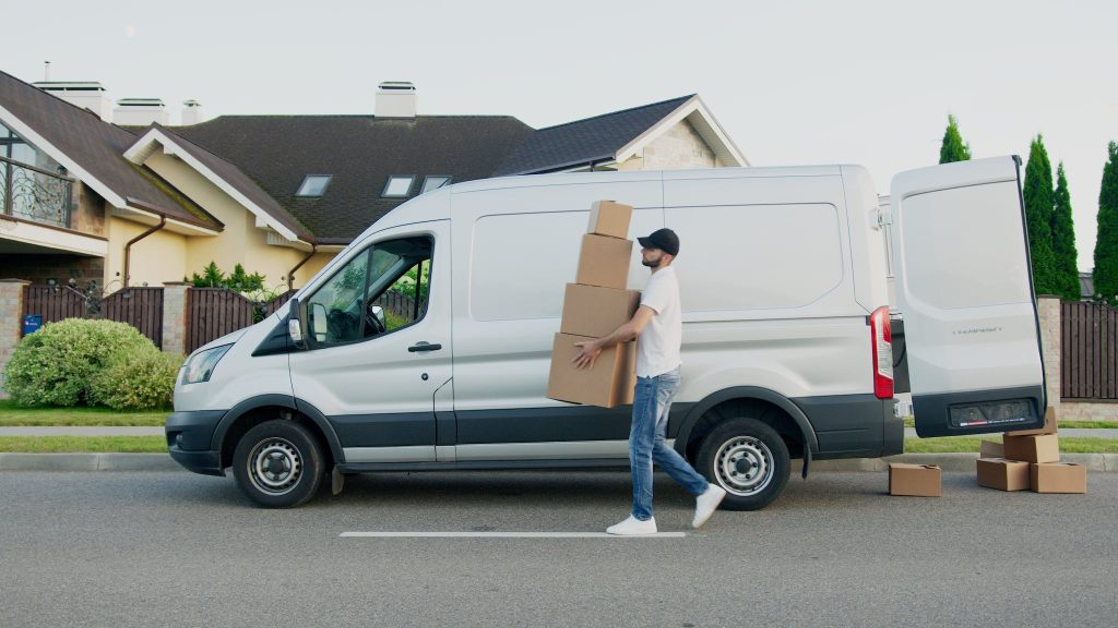 Veddys, Man Carrying Boxes Beside a Van